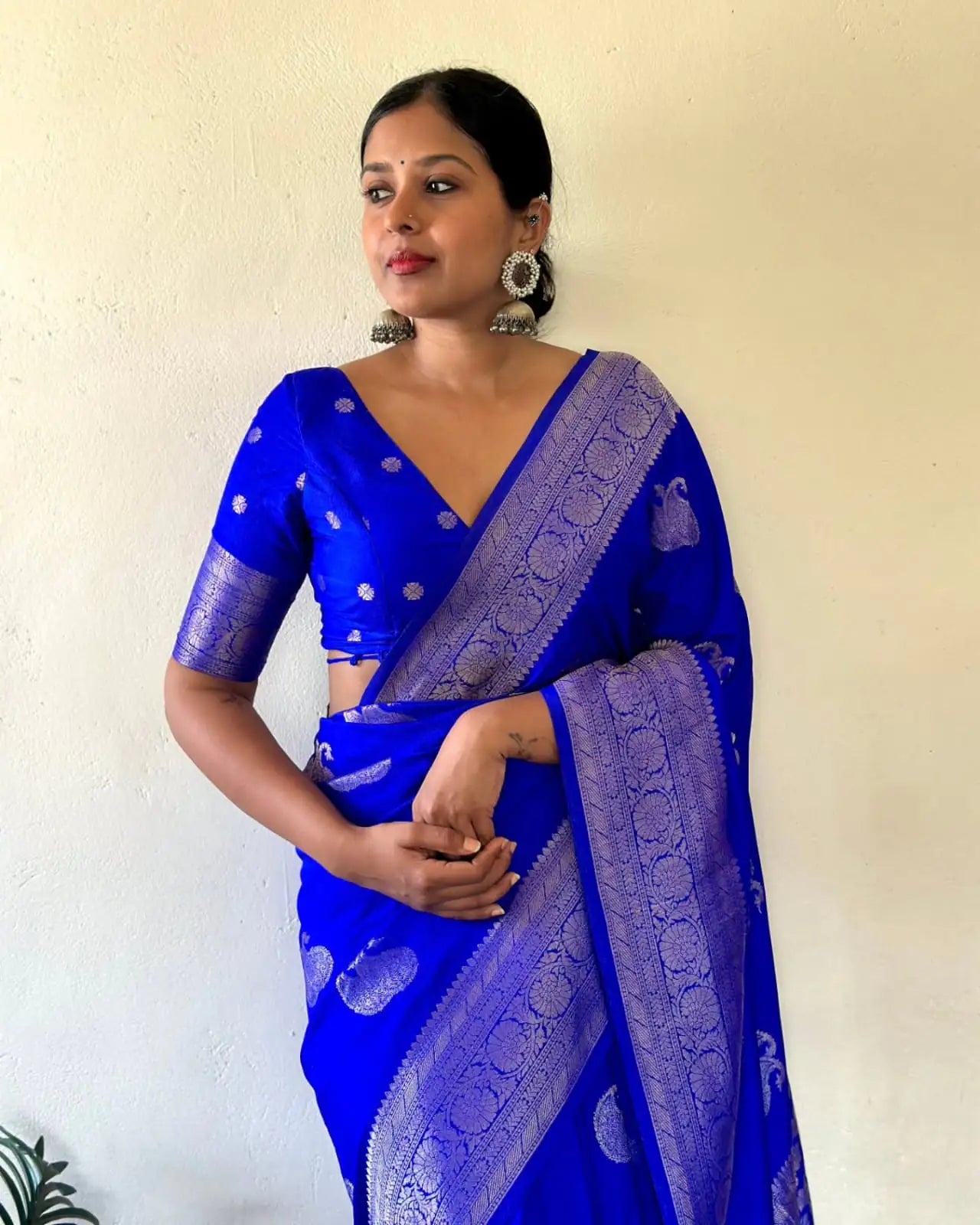 Woman wearing a blue saree with intricate patterns against a plain background
